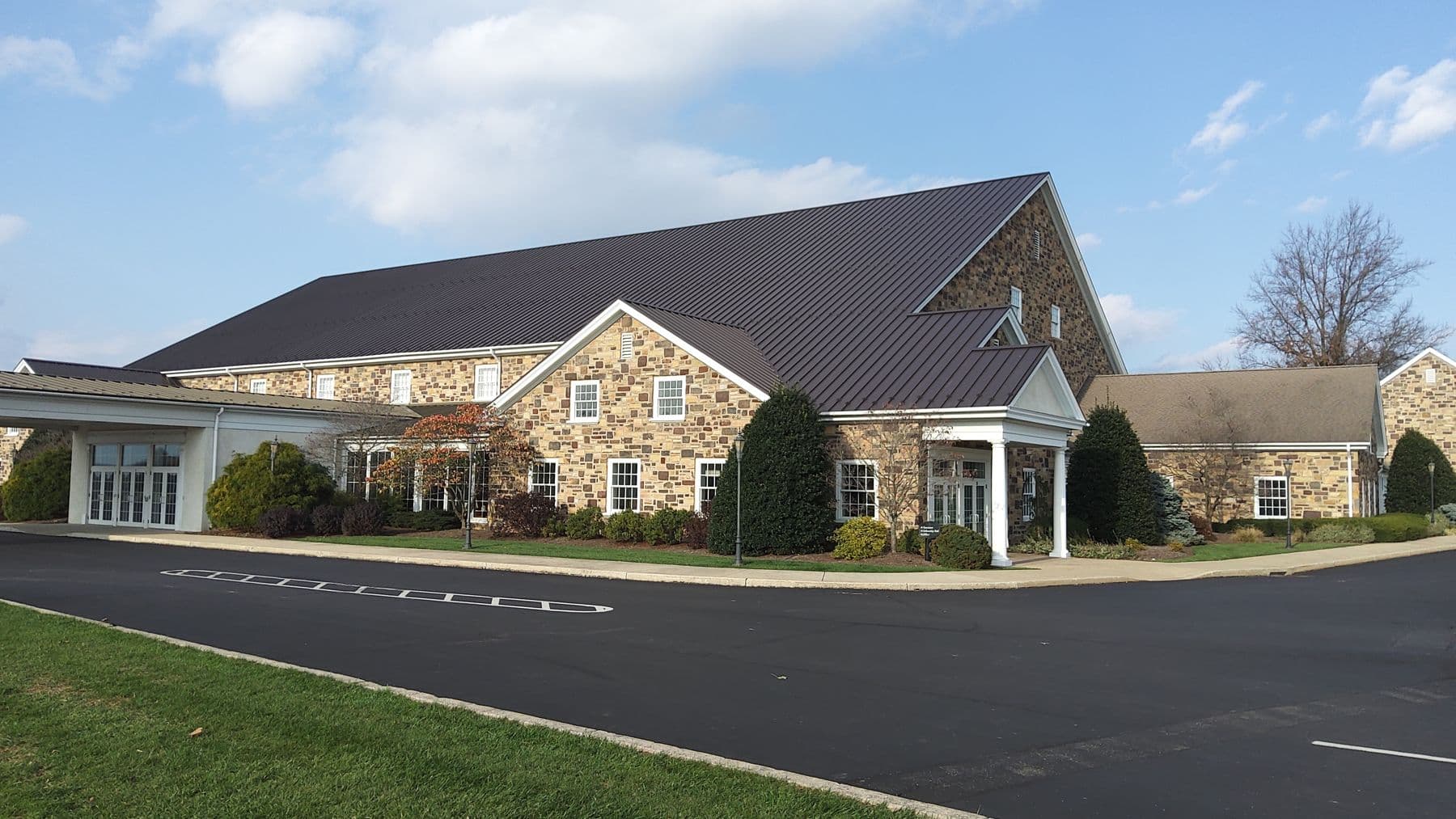 Stone church with a standing-seam metal roof by King's Roofing & Siding