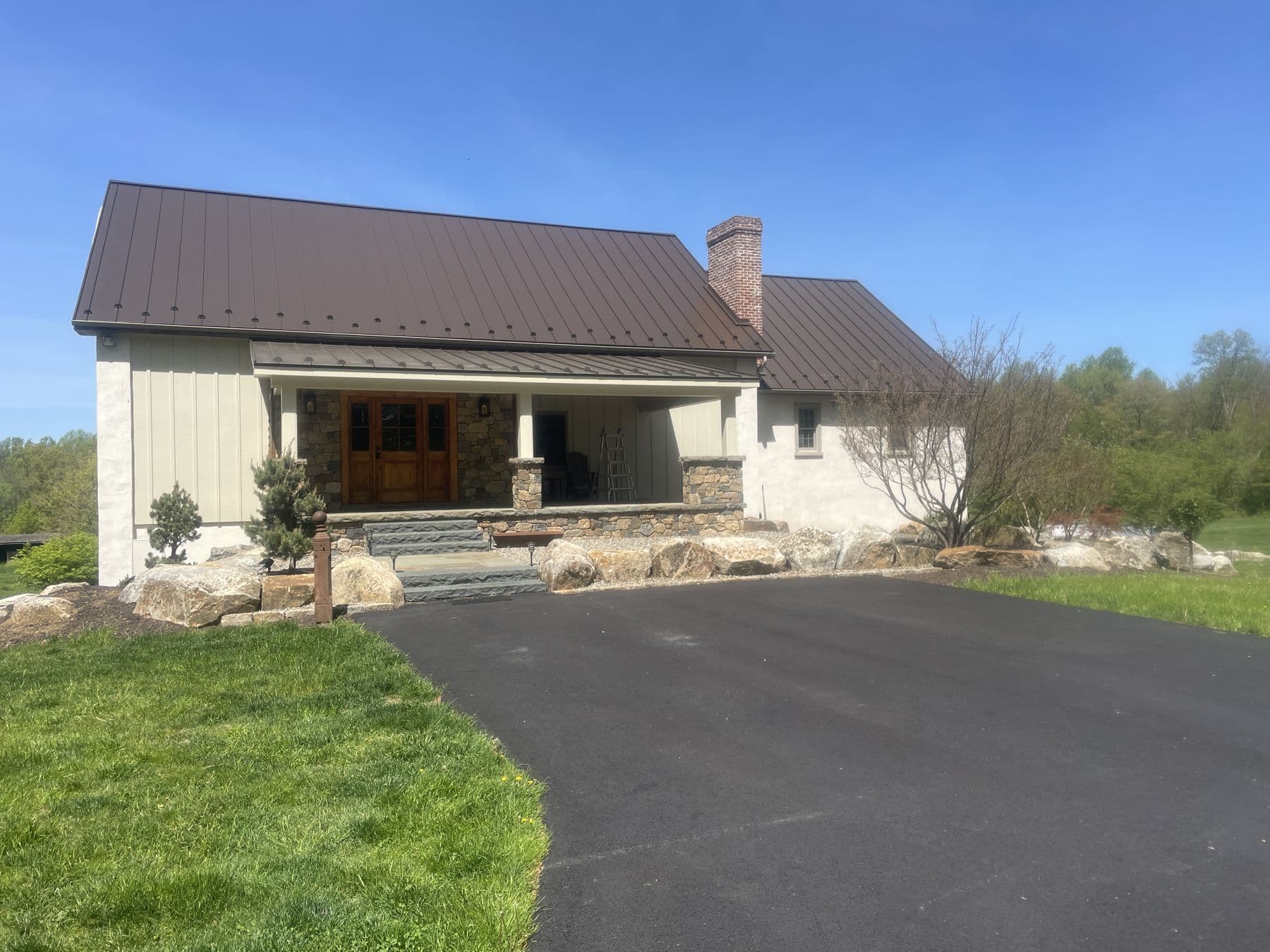 Board-and-batten home with standing-seam roof and stone entry